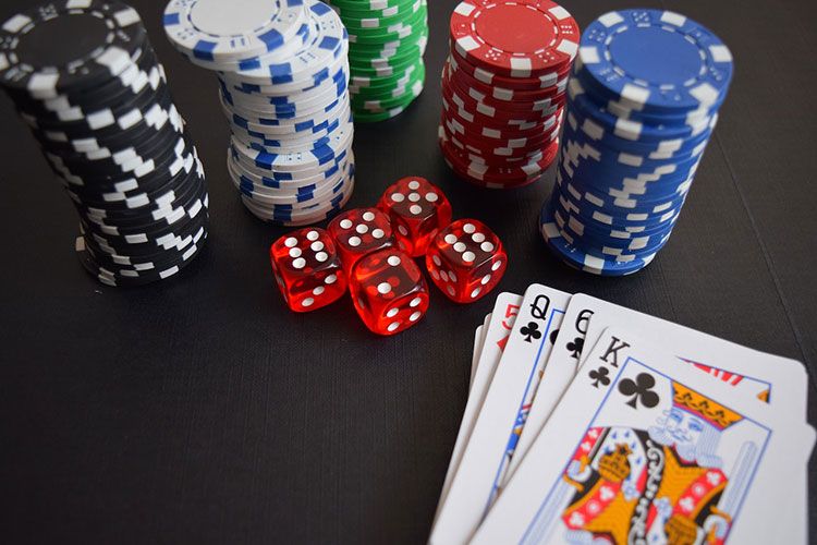 Picture of hand of cards with dice and stacks of back, white, green, red and blue poker chips