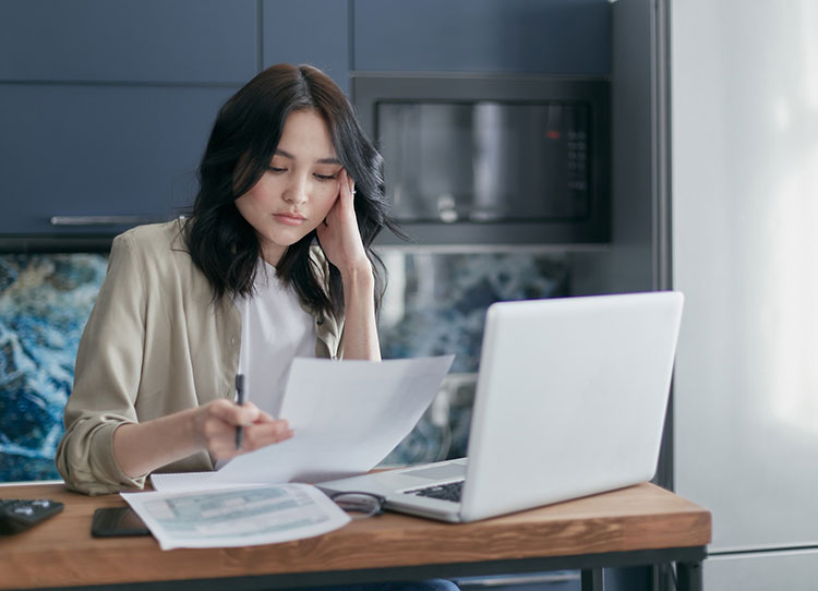 Image of woman sitting at wod kitchen table looking at taxes