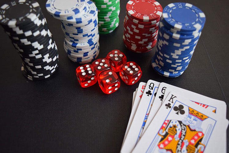 Picture of poker table with a stack of poker chips, dice, and hand of cards laid out