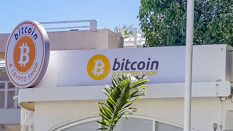 Picture of white bitcoin & crypto shop with a palm tree in front