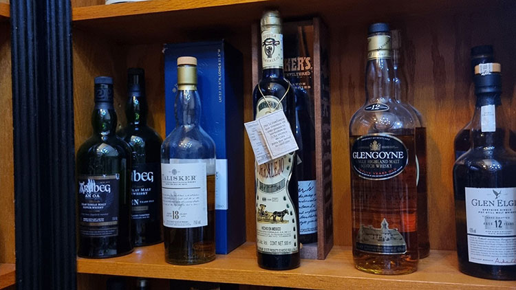 Shelf of alcohol behind a blue pulled back curtain