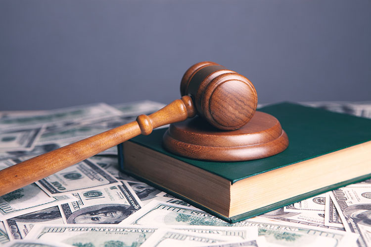 Image of gavel sitting on top of a book in a pile of money