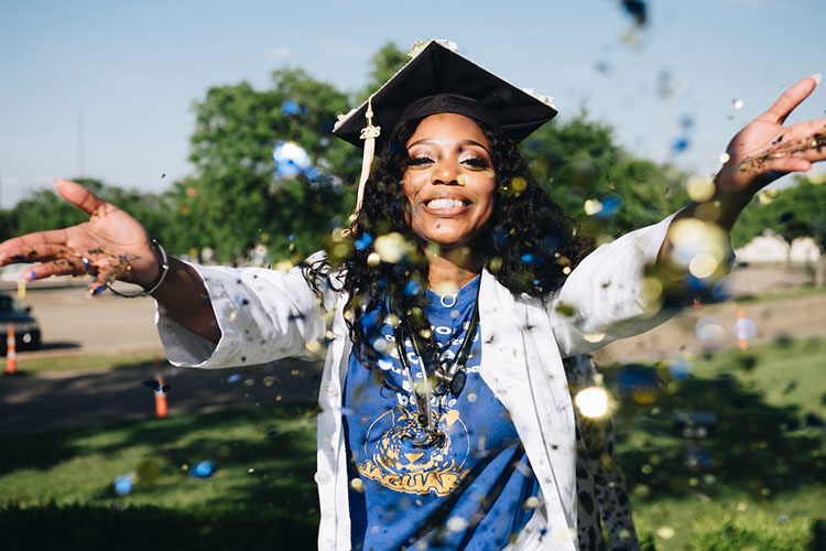 Woman in graduation cap throwing up glitter into the air