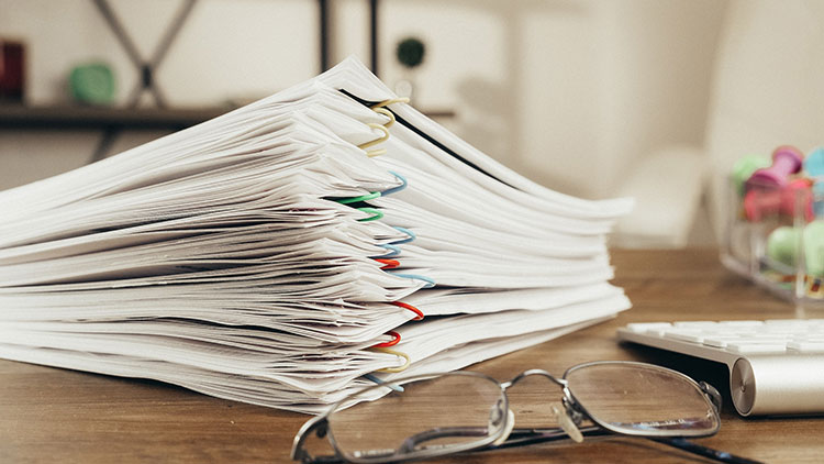 Image of stack of papers with paper clips on desk with glasses