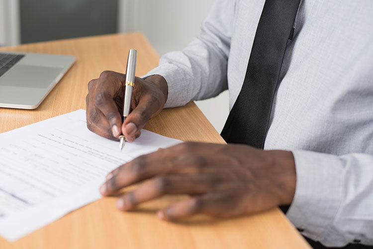 Man in tie holding a pen signing tax reports