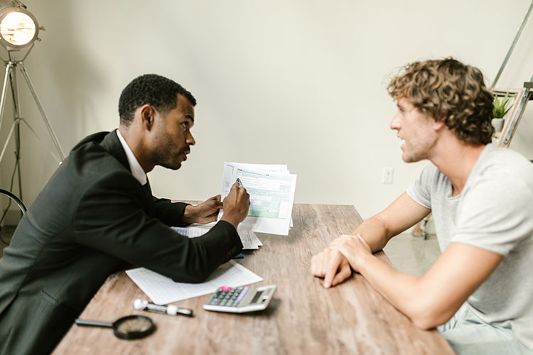 man and tax auditor on either side of desk reviewing paperwork