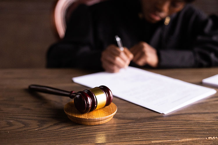 man filling out papers on table with a gavel