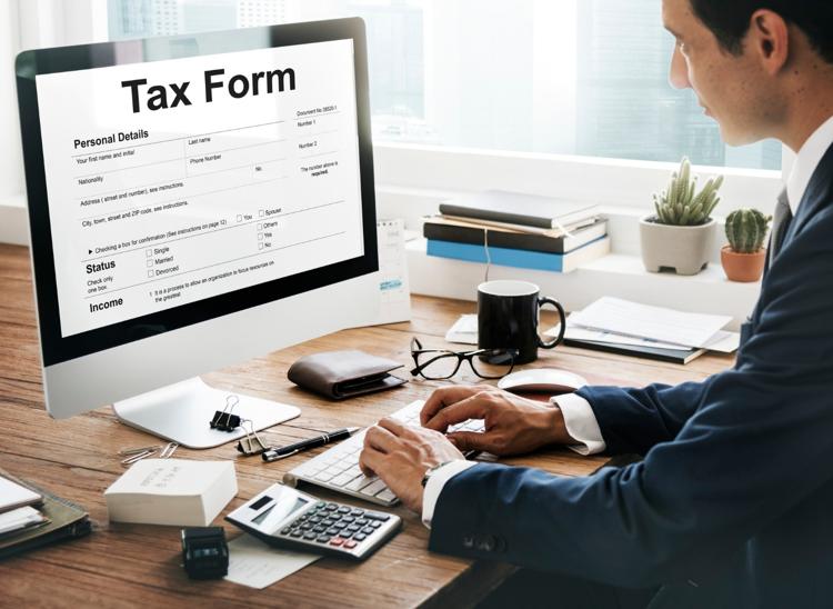 Man at a desk completing a tax form on a computer