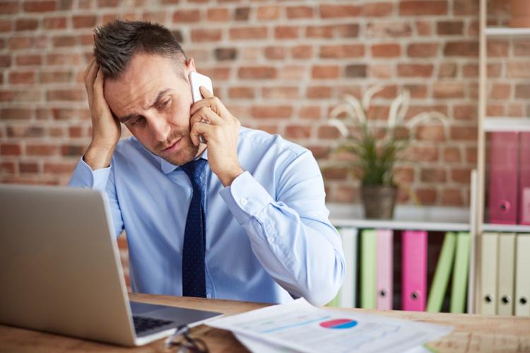 Businessman at work desk stressed out on phone