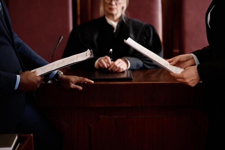 Prosecution and defense lawyers with documents standing opposite each other in front of judge