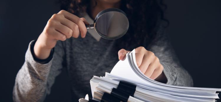 Businesswoman holding magnifying glass and documents