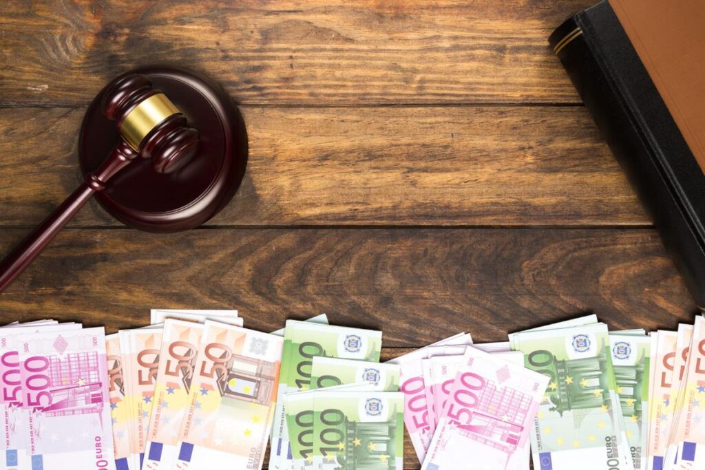 Top view of a judge's gavel, book and an arrangement of different denominations of Euros.