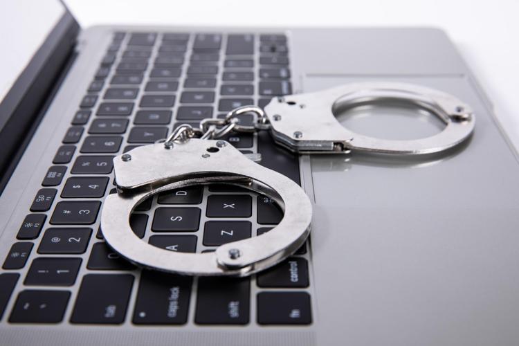Closeup shot of handcuffs lying on laptop keypad
