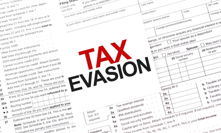 The words Tax Evasion printed on a white sticky attached to the sheets of a tax return